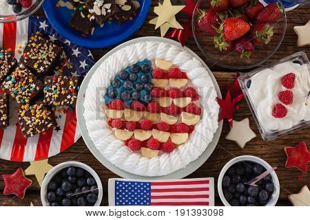 Fruitcake and various sweet foods arranged on wooden table with 4th July theme