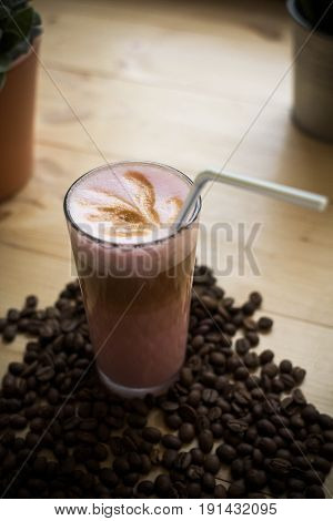 glass of coffee with some beans on the table