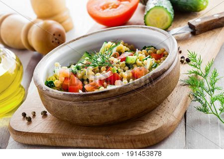 Delicious Israeli couscous Ptitim with vegetables on a white wooden table. Cooking of healthy vegetarian food for the meal. Traditional Moroccan cuisine.