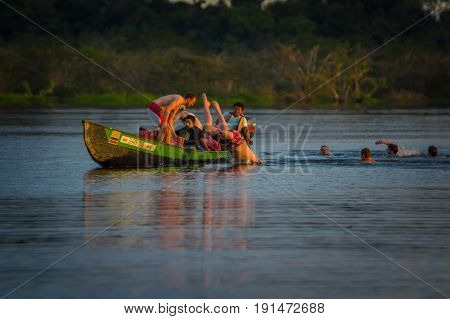 CUYABENO, ECUADOR - NOVEMBER 16, 2016: Young Tourists Jumping Into The Lagoon Grande Against The Sunset, Cuyabeno Wildlife Reserve, South America.