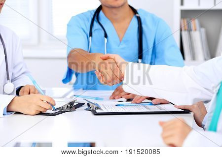 Doctors shaking hands to each other finishing up medical meeting.