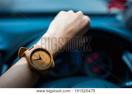 Business Woman Hand Wearing Wooden Wrist Watch. Her Holding Steering Wheel Car For Driving And Have