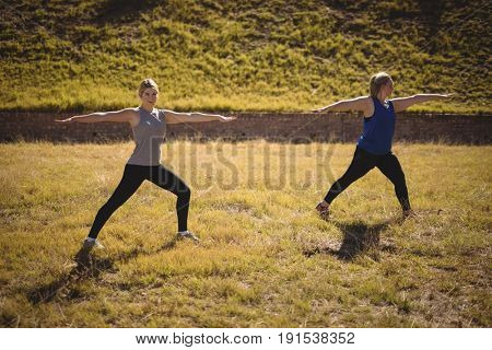 Beautiful women praising yoga during obstacle course in boot camp