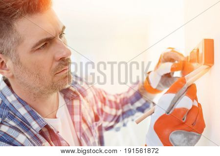 Mid-adult man marking on wall with level