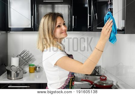 a woman cleans the kitchen wiping the microwave blue towel