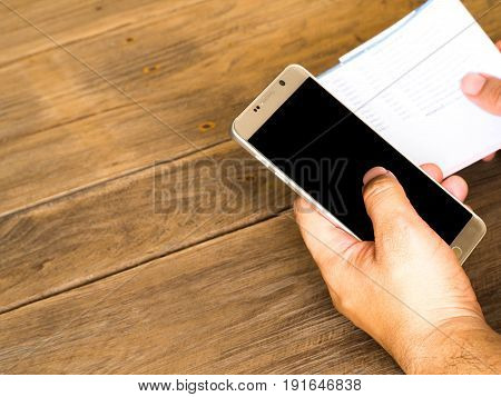 A man holding smart phone for using online banking app for paying credit card bill.At on the wood table in the backyard. mobile phone screen with Clipping Path