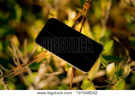 Mobile phone on old barbed wire and bright backgroup