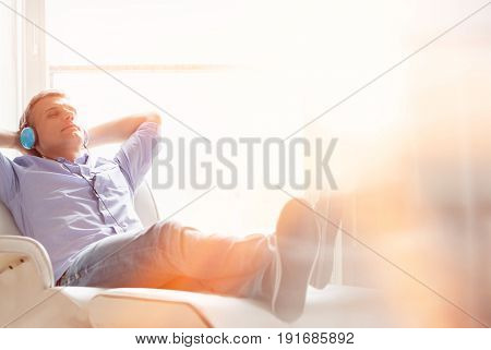 Full-length of relaxed Middle-aged man listening to music at home
