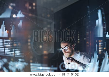 Concept of digital diagram, graph interfaces, virtual screen, connections icon.Young finance analist working at modern office.Man using contemporary laptop at night, blurred background.Horizontal