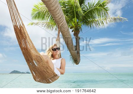 view of nice young lady swinging  in hummock on tropical beach