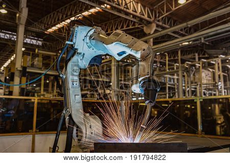 Close-up industrial robot is welding in a car factory