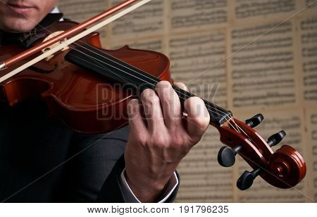 Violin player hands. Musician virtuoso violinist playing violin against the background of musical notes. Close up of musical instruments fiddle with fiddlestick