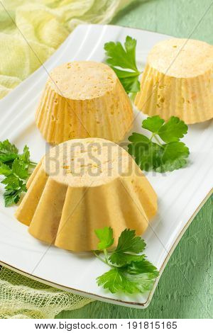 Tasty homemade carrot-chicken souffle cooked in double boiler. Souffle served on plate on green wooden table with yellow gauze napkin. Concept of dietary and healthy eating. Selective focus. Vertical