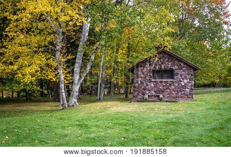 Tiny Stone House. Side view of a tiny stone house with autumn foliage in the yard. This is a historical structure in a national forest and not private property.