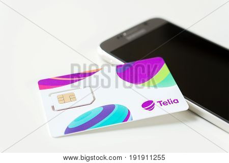 JYVASKYLA, FINLAND - JUNE 19, 2017: Brand new Telia sim card on smartphone on table. Telia is a telephone company and mobile network operator in Europe. Illustrative editorial.