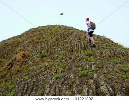 Hiker Climbing On Sharp Peak Of Basalt Formation Of Volcano
