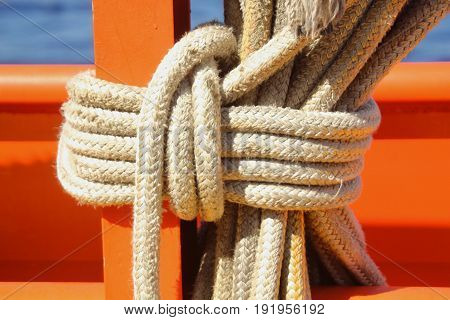 Big ropes tied in a tight knot
Sturdy white ropes tied in a secure tight knot against a wood post