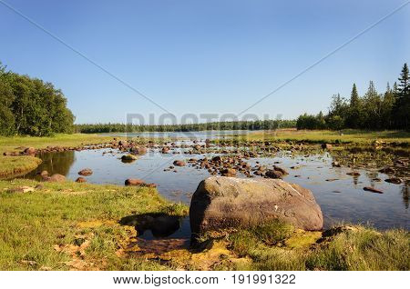 Large stones on the shore of the White Sea Bay during the low tide Bolshoy Solovetsky Island sunny summer day