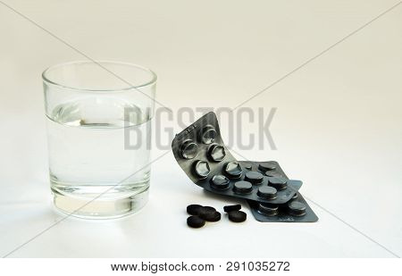 Activated Carbon Pills And Glass Of Water.