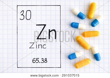 Handwriting chemical element Zinc Zn with pills. Close-up.