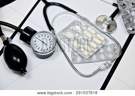 Phonendoscope And Tonometer  With A Folder With White Sheets Of Paper And Pills  On A White Backgrou