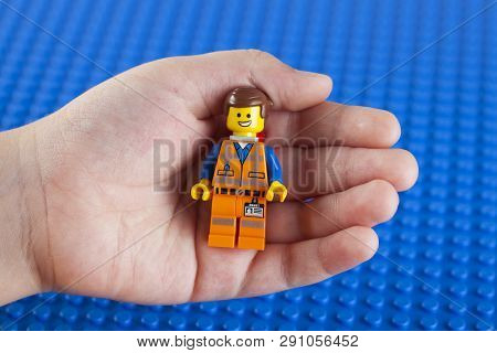 Tambov, Russian Federation - July 26, 2014 Lego Hard Hat Emmet Minifigure In Child Hand Against Lego