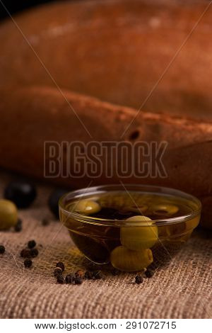 Fresh Bread Baguette With Olive Oil, Olives. Cheese And Rosemary On Wooden Background. Teasty Breakf