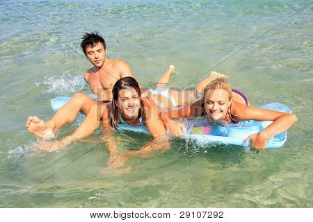 Gruppo di tre amici - uomo e donna - sulla spiaggia avendo un sacco di divertimento in vacanza in Grecia