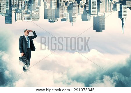 Businessman Looking Into The Distance On Abstract Sky Background With Clouds And Upside-down City Sk