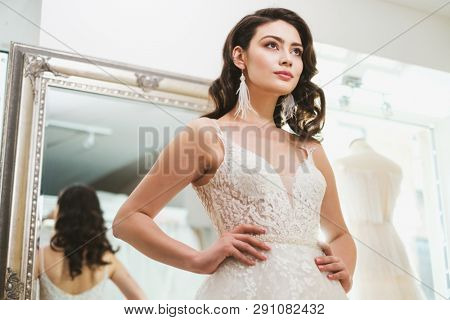 Beautiful bride choosing wedding dress in a wedding salon