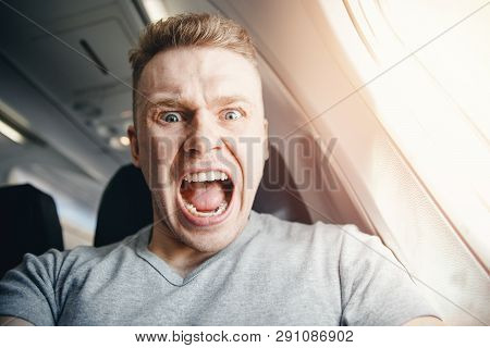Male Passenger In Plane Screams And Cries, Aerophobia. Background Of Porthole. Concept Fear Of Flyin