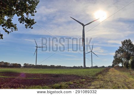 View On Alternative Energy Windmills In A Windpark In Northern Germany In Front Of A Blue Sky