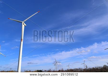 View On Alternative Energy Windmills In A Windpark In Northern Germany In Front Of A Blue Sky