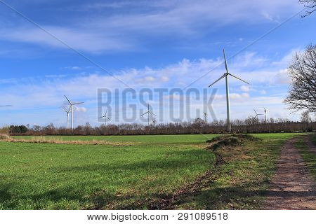 View On Alternative Energy Windmills In A Windpark In Northern Germany In Front Of A Blue Sky