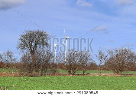 View On Alternative Energy Windmills In A Windpark In Northern Germany In Front Of A Blue Sky