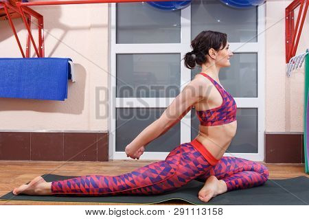 Young Sporty Woman Practicing Yoga, Doing Mahamudra Stretching Position In A Fitnes Club