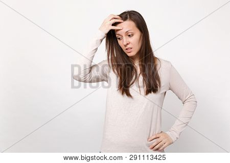 Portrait Of Preoccupied Young Woman In Light Clothes Looking Down, Putting Hand On Head Isolated On 