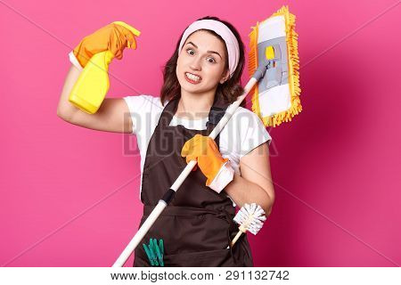 Close Up Of Young Fun Housewife In Orange Gloves, Brown Apron, White T Shirt, Hair Band. Housekeeper