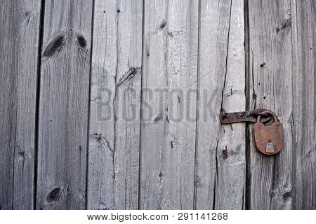 Rusty Padlock On A Wooden Gate Is Closed