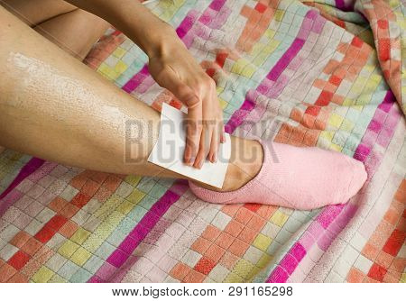 Woman And Her Hairy Leg On A Multi-colored Towel. Girl In Anticipation Of Procedures Of Depilation B