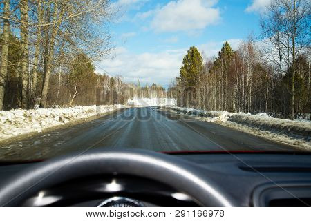 View Of The Road Through The Windshield. Snow On The Sidelines. Wet Asphalt Road. Blue Sky With Clou