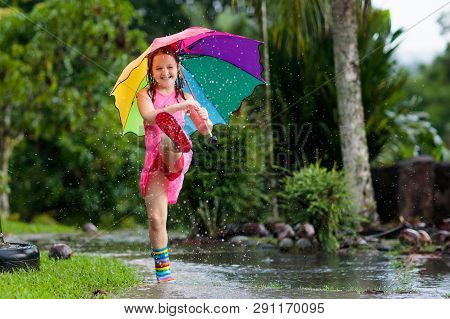 Kid With Umbrella Playing In Summer Rain.
