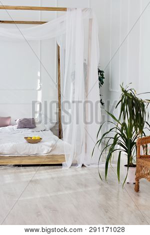Beautiful Bright Room And A Four-poster Bed. Cozy Bedroom In Light Colors With A Wooden Floor, A Lar