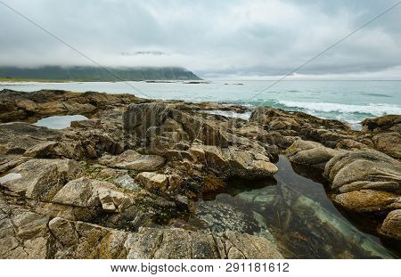 Summer Cloudy View Of The Beach With Pool In Middle Of Stones ( Ramberg, Norway, Lofoten).