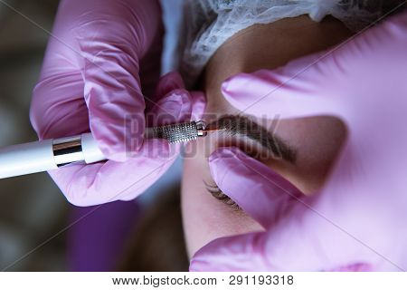 Permanent Makeup For Eyebrows. Microblading Brow. Beautician Doing Eyebrow Tattooing For Female Face
