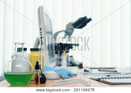 Laboratory Table With Microscope, Flasks And A Desktop Computer Above On A Window Light Background. 