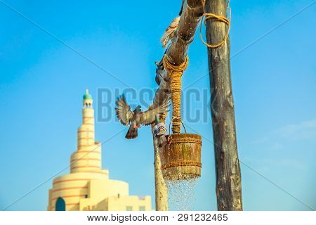 Pigeon Flying At Old Well Fountain, Famous Tourist Place In The Middle Of Souq Waqif In Front Of Mos