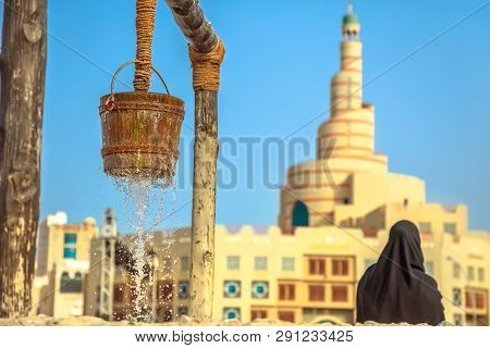 Closeup Of Flowing Water At Old Fountain At Souq Waqif In Doha Center With Woman Behind With Dressed