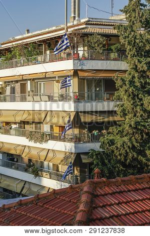 Greek Flags Waving On Balconies For A National Celebration. Blue And White Greek Flags With Cross Ou