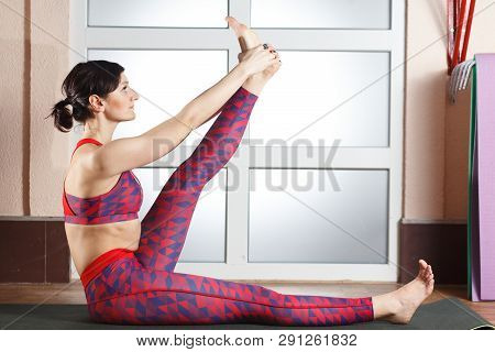 Young Sporty Woman Practicing Yoga, Doing Mahamudra Stretching Position In A Fitnes Club